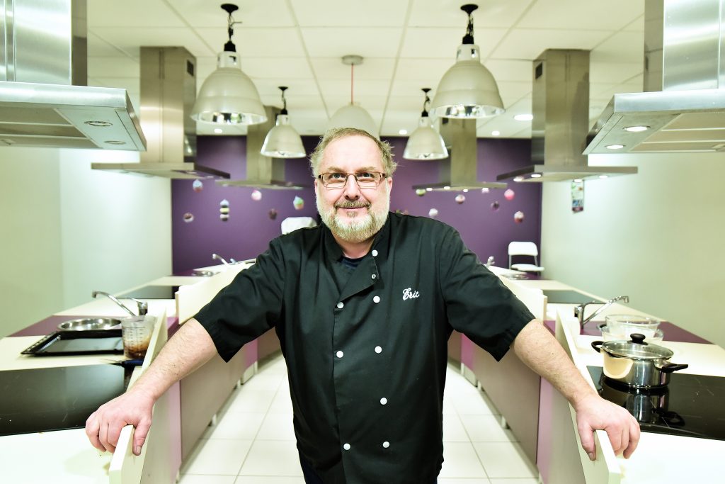 Éric Wehrle, chef cuisinier et fondateur de Régal Tes Amis, en veste de chef dans son atelier de cuisine